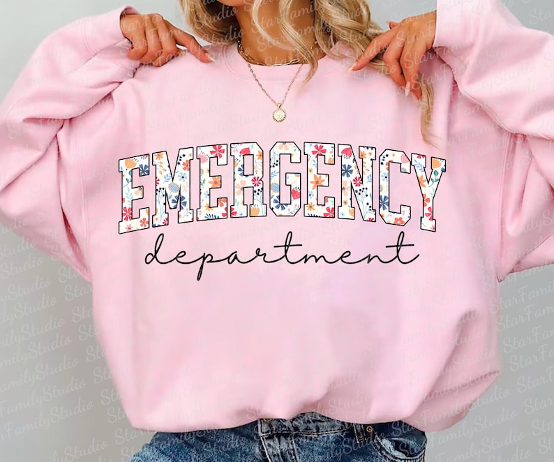 K&ouml;nnte beinhalten: Rosafarbener Pullover mit einem Blumendruck, auf dem "EMERGENCY department" in wei&szlig;en Buchstaben steht.