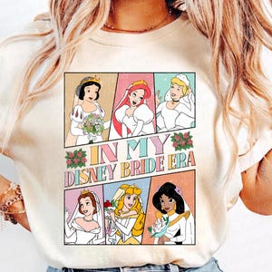 Peut inclure: Un t-shirt blanc avec un graphique color&eacute; repr&eacute;sentant des princesses Disney en robes de mari&eacute;e. Le texte "In My Disney Bride Era" est imprim&eacute; sur le t-shirt.
