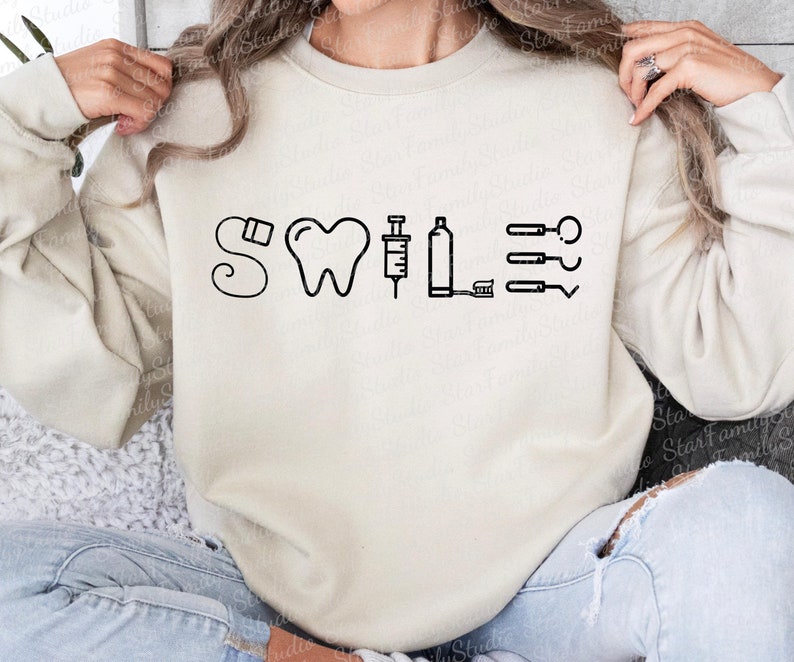 May include: A white sweatshirt with a black graphic design that says "Smile" with dental tools and a tooth.