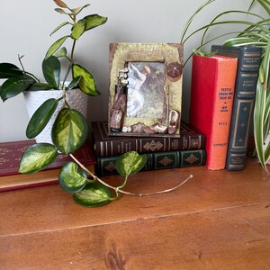 Peut inclure: Un cadre photo rectangulaire à la finition texturée et vieillie, orné d'éléments décoratifs tridimensionnels sur le thème du golf, notamment un sac de golf avec des clubs, une casquette et une chaussure de golf fixés sur le bord du cadre.