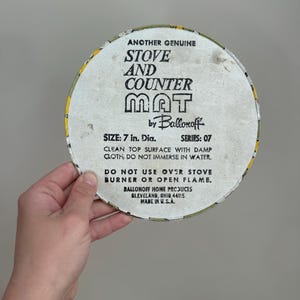 May include: A round stove and counter mat with a yellow and white border. The mat is 7 inches in diameter and features the text "Stove and Counter Mat" and "Ballonoff Home Products".