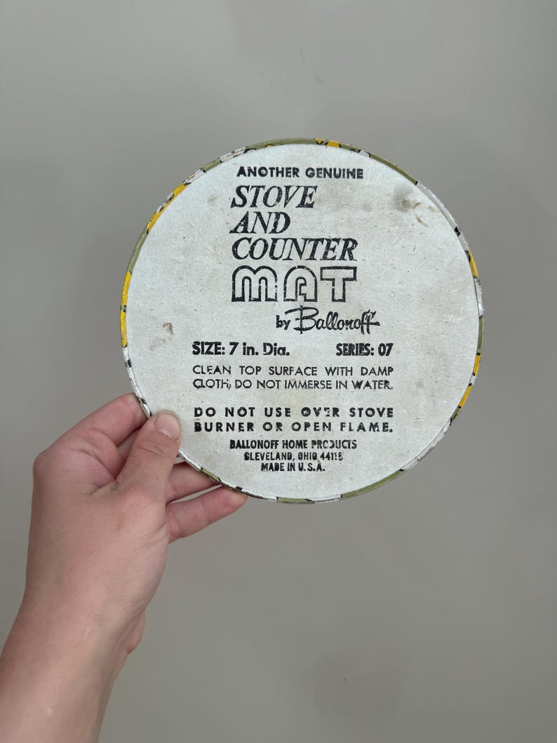 May include: A round stove and counter mat with a yellow and white border. The mat is 7 inches in diameter and features the text "Stove and Counter Mat" and "Ballonoff Home Products".