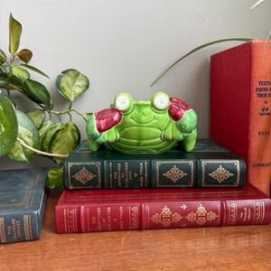 Könnte beinhalten: Ein Set aus drei Keramikbechern mit gesprenkelter, matter Oberfläche. Die Becher sind in Creme-, Hellgrau- und Dunkelgrautönen gehalten. Jeder Becher hat ein schlichtes, minimalistisches Design und einen abgerundeten Henkel.