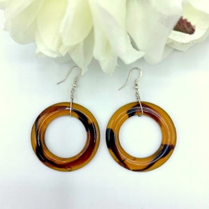 May include: A pair of brown and black tortoise shell hoop earrings with silver hooks.