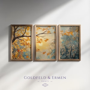 May include: Three framed art prints depicting autumnal trees. The artwork shows branches with yellow and orange leaves against a backdrop of blue and yellow hues. The prints are in wooden frames. The text "GOLDFELD & ERMEN - PRINTS" is at the bottom.