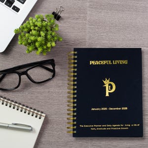 Può includere: Un'agenda blu navy rilegata a spirale con scritte dorate che recitano "PEACEFUL LIVING" e "Gennaio 2025 - Dicembre 2026". La copertina presenta una "P" dorata con una corona. Visibili anche un laptop, occhiali, una piccola pianta e un blocco note.