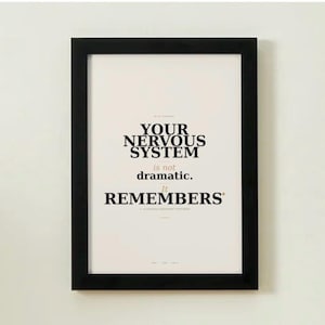 Könnte beinhalten: Gerahmter Druck mit dem Text "YOUR NERVOUS SYSTEM is not dramatic. It REMEMBERS" in schwarzer Schrift auf cremefarbenem Hintergrund. Der Druck befindet sich in einem schwarzen Rahmen und ist an einer weißen Wand befestigt.