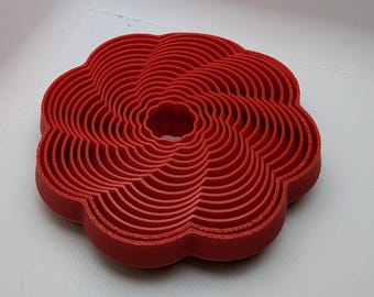 Puede incluir: Un juego de cortadores de galletas de plástico rojo en forma de flor, anidados en un patrón circular.
