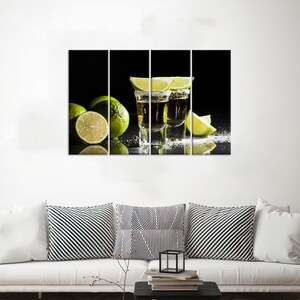 May include: Two shot glasses filled with a golden liquid, garnished with lime wedges, on a black background with lime slices scattered around.