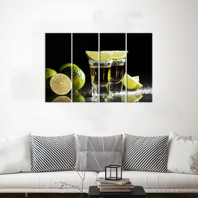May include: Two shot glasses filled with a golden liquid, garnished with lime wedges, on a black background with lime slices scattered around.