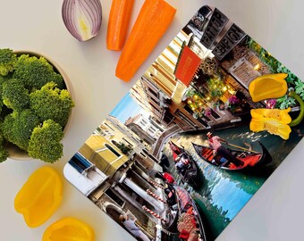 May include: A colorful cutting board with a photo of a canal in Venice, Italy. The image shows gondolas, buildings, and a blue sky. The cutting board is made of durable material and is perfect for preparing meals.