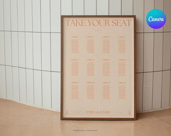 May include: A rectangular wedding seating chart sign in a dark wood frame with a light beige background and orange text. The sign features the heading TAKE YOUR SEAT, a list of twelve tables with guest names, and the names EMILY & DAVID at the bottom.