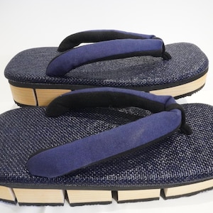 May include: A pair of blue and brown Japanese sandals with a woven fabric upper and a wooden sole.