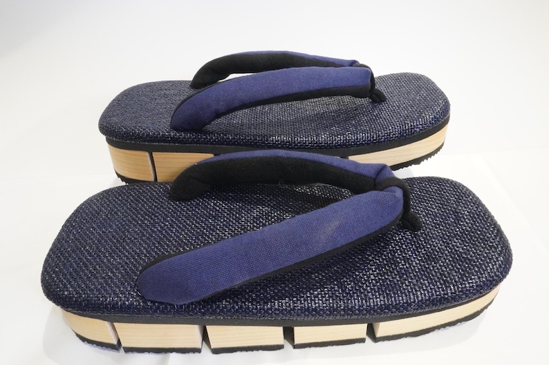 May include: A pair of blue and brown Japanese sandals with a woven fabric upper and a wooden sole.