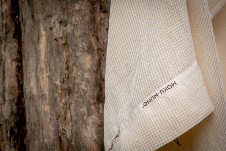 May include: A white waffle weave towel with a brown label that reads "MOKU-NUNO".