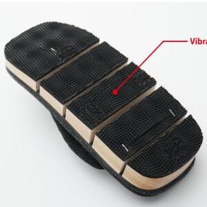 May include: Close-up of the bottom of a black sandal with a brown wooden base. The sole is made of black rubber with a textured pattern and the text "Vibram Sole" is written in red.