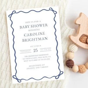 Op de afbeelding: Een uitnodiging voor een babyshower met marineblauwe tekst en een decoratieve rand. De uitnodiging luidt "Doe mee voor een babyshower ter ere van Caroline Brightman" en bevat de datum, tijd en locatie. Een houten schommelpaard en een kralen bijtring liggen ernaast.