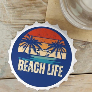 Op de afbeelding: Een ronde blauwe en witte flessenopener met een retro zonsondergangontwerp en de tekst "Beach Life".