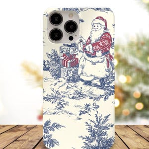 May include: A phone case featuring a Christmas-themed design. The case has a cream-colored background with a blue and red illustration of Santa Claus, gifts, and winter foliage. The case is made of a hard, protective material.