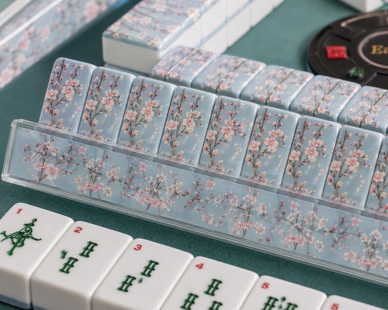 Close-up of cherry blossom Mahjong tiles showcasing the soft blue background with elegant pink cherry blossom branches and detailed American Mahjong tile faces.