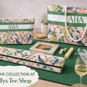 May include: A collection of matching accessories with a floral and bird pattern, including a tote bag, cosmetic bag, and a zippered case. Each item has a white stripe with the initials "AHA". A green mat displays game pieces and a wine glass.