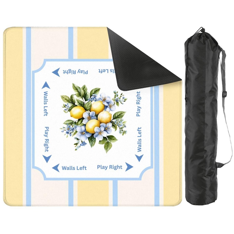 Yellow, cream, and blue striped mahjong mat with lemon floral center shown with carrying storage bag. The padded square mat includes directional gameplay text and a non-slip black backing corner folded upward.