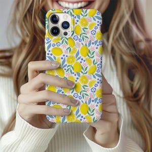 May include: A white phone case with a pattern of yellow lemons, green leaves, and pink and blue flowers.