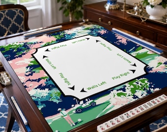 May include: A square mahjong table mat featuring a golf-themed illustration with a golfer and cart. The center white area includes black arrows and text reading Play Right and Walls Left. The border displays a colorful floral and golf course pattern.