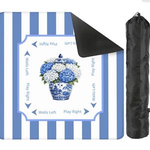 Blue and white striped mahjong mat with hydrangea chinoiserie vase design shown with rolled black carrying sleeve on a clean white background.