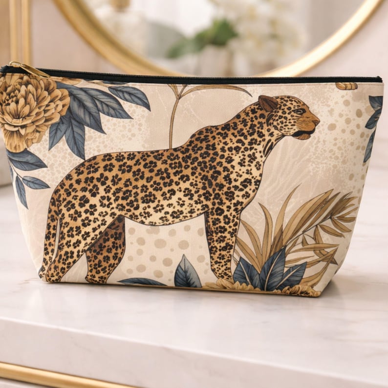 Leopard floral accessory pouch with gold botanical design sitting on a marble table in an elegant neutral setting.