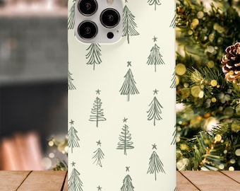 May include: A phone case with a cream-colored background and a repeating pattern of green Christmas trees. Each tree is topped with a small star. The case has a camera cutout and is sitting on a wooden surface.