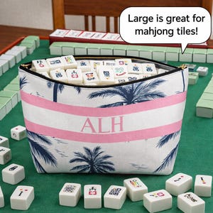 May include: A white and pink striped zippered pouch with a palm tree design, filled with mahjong tiles. The pouch has the initials "ALH" in pink. The text "Large is great for mahjong tiles!" is in a speech bubble.