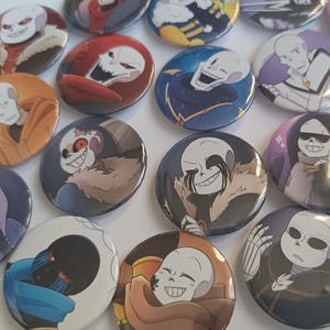 Peut inclure: Une collection de 15 badges ronds en forme de bouton représentant divers personnages du jeu vidéo populaire Undertale. Les badges sont colorés et présentent différents personnages, notamment Sans, Papyrus et Undyne.