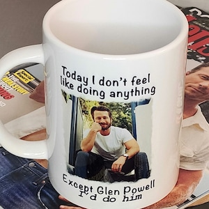 May include: White ceramic coffee mug with a black graphic that says "Today I don't feel like doing anything except Glen Powell I'd do him". The graphic includes a photo of a man with a beard and a white t-shirt.