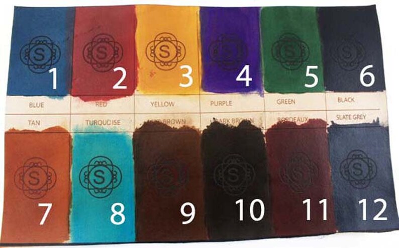 May include: A color chart displaying twelve swatches of dyed leather. The colors include blue, red, yellow, purple, green, black, tan, turquoise, brown, dark brown, bordeaux, and slate grey. Each swatch has a decorative emblem and a number.