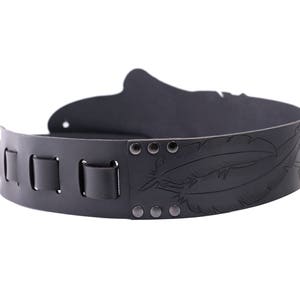 May include: A black leather belt with a decorative feather design. The belt features a series of rectangular loops and is secured with rivets. The design is embossed into the leather, creating a textured appearance. This belt is suitable for various outfits.