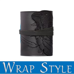 May include: Black leather wrap-style journal with a raven design. The journal features an embossed raven head and feather details. A leather strap wraps around the journal to keep it closed. The text "WRAP STYLE" is at the bottom of the image.