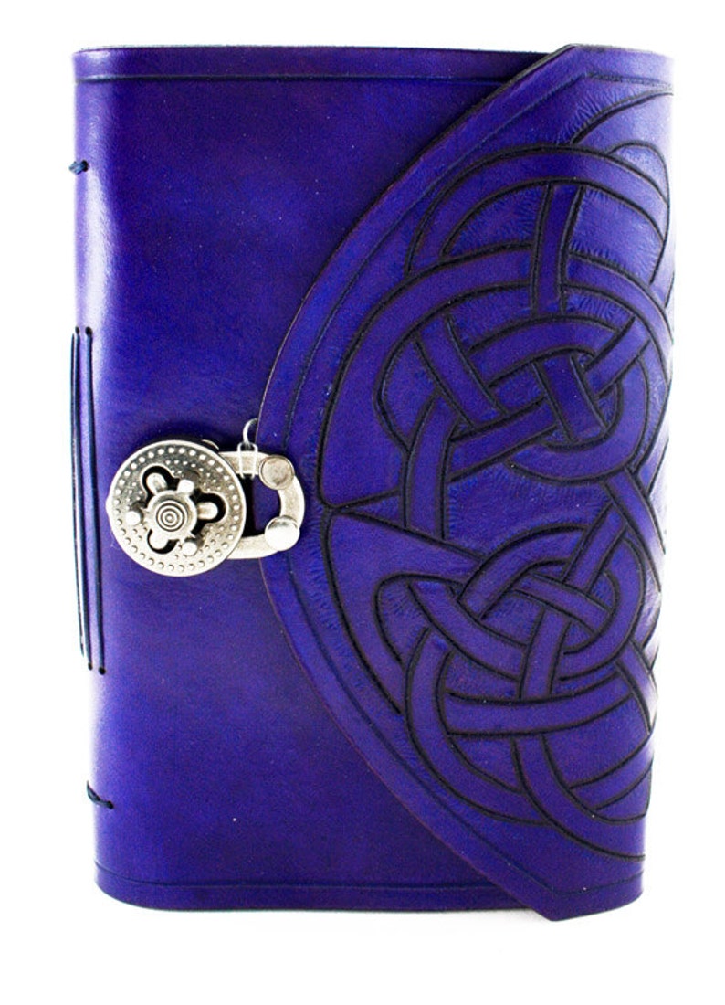 May include: A deep purple leather journal with a Celtic knot design embossed on the cover. The journal features a silver-colored clasp and a stitched spine. The cover has a flap closure.