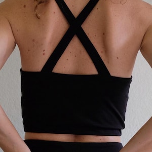 May include: A black crop top with a criss-cross back strap and matching black trousers.