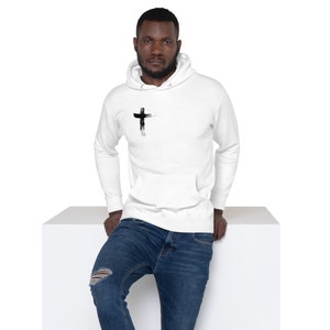 Könnte beinhalten: Ein weißer Hoodie mit einem schwarzen Kreuz-Motiv auf der Vorderseite. Der Hoodie hat eine Kapuze mit Kordelzug und eine Kängurutasche.