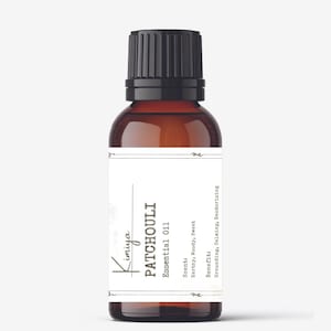 May include: A brown glass bottle with a black cap, labeled "Kimiya PATCHOULI Essential Oil". The label also includes the scent and benefits: "Scent: Earthy, Woody, Sweet" and "Benefit: Grounding, Calming, Deodorizing".