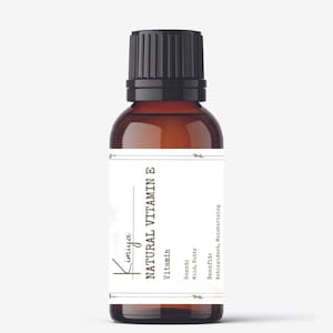 May include: A brown glass bottle with a black cap, labeled "Kimiya NATURAL VITAMIN E Vitamin". The label also includes the scent, "Mild, Nutty", and the benefit, "Antioxidant, Moisturizing".
