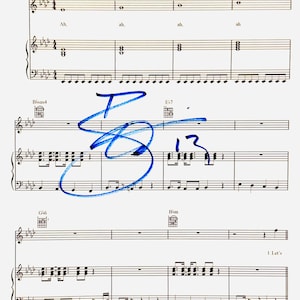 Op de afbeelding: Een bladmuziekpagina met zwarte muzieknotatie op een witte achtergrond, inclusief akkoorddiagrammen voor F7, Bbsus4, E7, G6 en Bbm. Een opvallende blauwe inkt-handtekening en het getal 13 staan over de notenbalken geschreven.