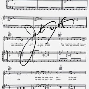 May include: A black and white sheet music page for the song Fortunate Son, featuring lyrics such as Some folks are born made to wave the flag and Ooh, they're red, white and blue, with a large, bold black ink signature overlaid across the center.