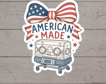 Puede incluir: Una pegatina que muestra una incubadora médica con un bebé dentro, rematada con un gran lazo con un patrón de estrellas y rayas rojas, blancas y azules. El texto AMERICAN MADE está impreso en letras azules y rojas, con pequeñas estrellas.