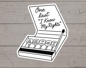 Puede incluir: Una pegatina en blanco y negro de una caja de cerillas abierta. El texto en la tapa dice One last "I Know My Rights". Dentro hay cinco cerillas con las etiquetas: Am I being detained?, I don't answer questions, I want a lawyer, I don't consent, I know my rights.