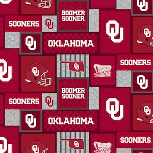 May include: Red and gray fabric with a repeating pattern of the University of Oklahoma logo, the words "Sooners" and "Boomer Sooner", and the state of Oklahoma.