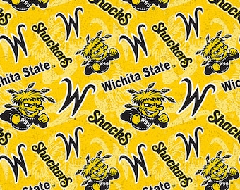 May include: Yellow fabric with a repeating pattern of a black "W" for Wichita State University, the words "Shockers" and "Wichita State", and a cartoon mascot with a yellow face and black hair.