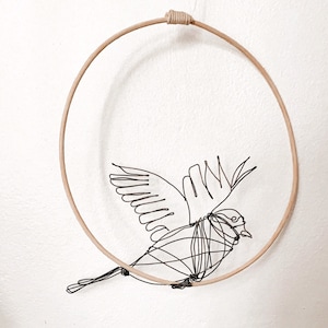 Wire bird. Black wire bird on a rattan perch. Animal sculpture, wire sculpture. Unique piece.