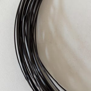 May include: A coil of black wire, likely used for crafting or jewelry making.